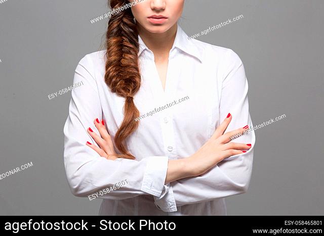 Female with hair braids style. Modern hairstyle in studio. Closeup portrait of woman with her arms crossed or folded over white background
