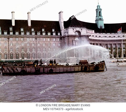 A London Fire Brigade fireboat in action on the River Thames outside County Hall, London