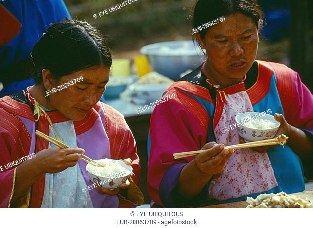 Two Lisu women eating at the village priests house for the New Years festival