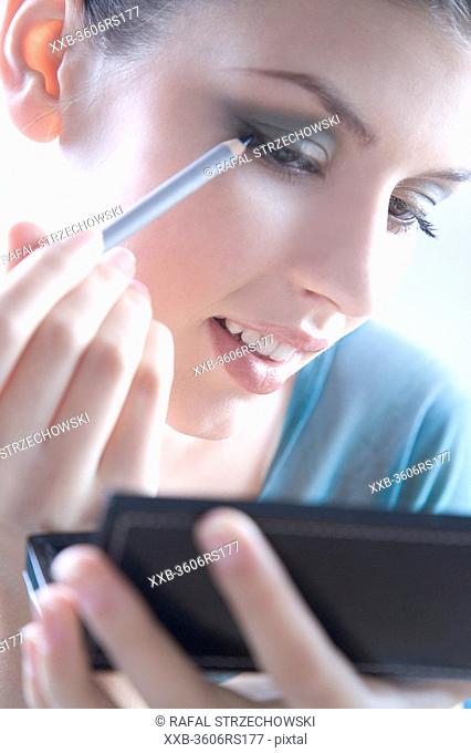 young woman using eyeliner