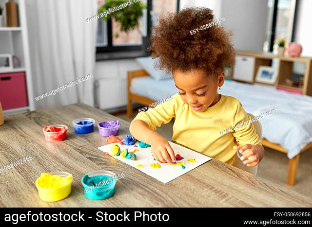 little girl with modeling clay playing at home
