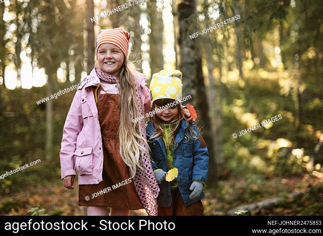 Smiling sisters in forest