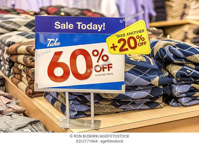 Sign indicates discounts on clothing in retail clothing bargain store