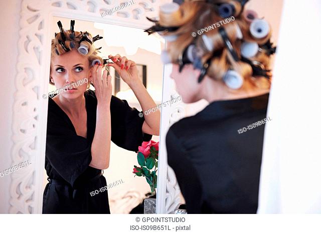 Mirror image of woman putting in hair rollers