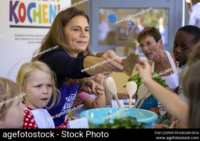 09 September 2022, Brandenburg, Potsdam: TV chef Sarah Wiener eats crispbread with homemade herb butter with the children at a press event to present the ""I...