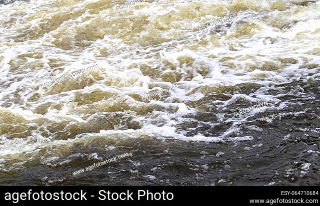 River rapids. Close up abstract background of falling water. Water flows over river rocks. A beautiful powerful stream of a stormy mountain river