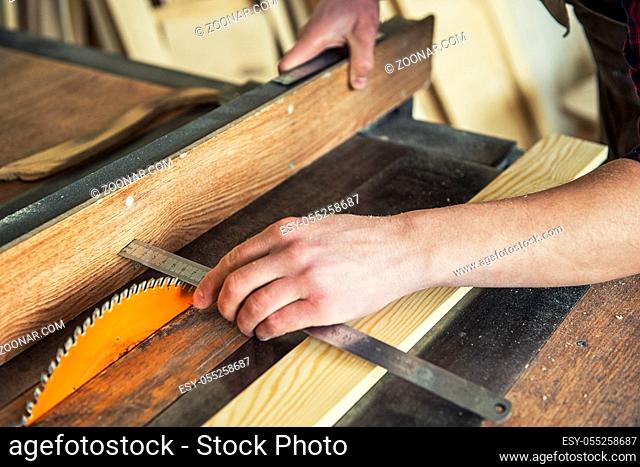 Construction worker cutting wooden board with circular saw