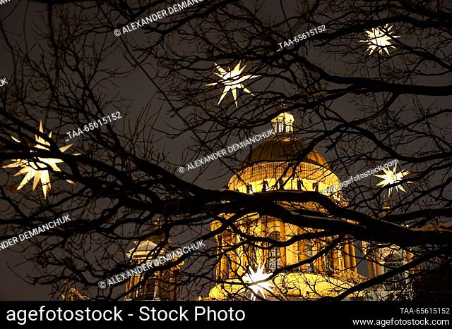 RUSSIA, ST PETERSBURG - DECEMBER 10, 2023: Star-shaped lights hang from tree branches, with St Isaac's Cathedral in the background