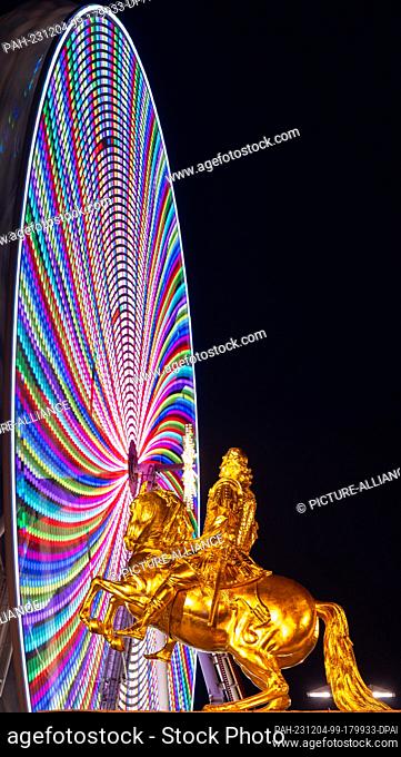 04 December 2023, Saxony, Dresden: The equestrian statue of Augustus the Strong, the so-called Golden Horseman, stands in front of a Ferris wheel