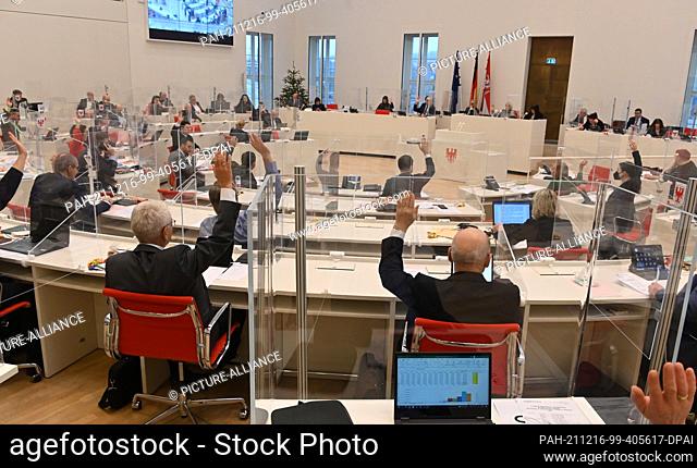 16 December 2021, Brandenburg, Potsdam: The MPs raise their hands to vote. The deputies discuss, among other things, laws to improve day care and to improve the...