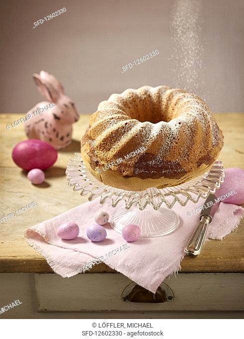 A marble Bundt cake dusted with icing sugar with Easter decorations