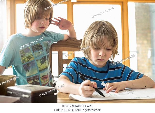 England, London, Hackney. Seven year old boy drawing at the table