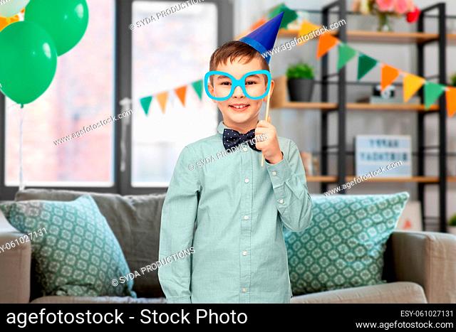 boy in birthday party hat with glasses at home