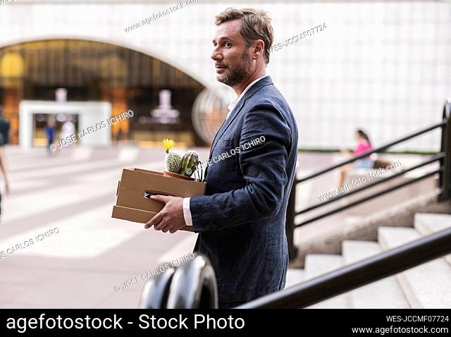 Businessman with cardboard box moving down steps