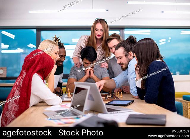 a multiethnic group of business people playing chess while having a break in modern startup office