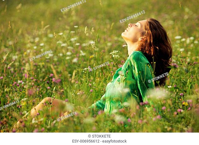 Young beautiful woman enjoying nature in the flowers field