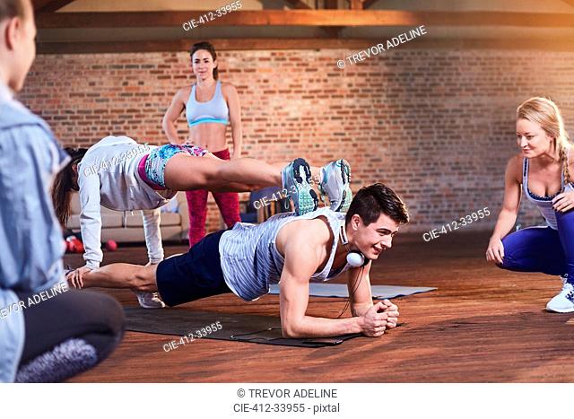 Young man and woman practicing stacked plank pose in gym studio