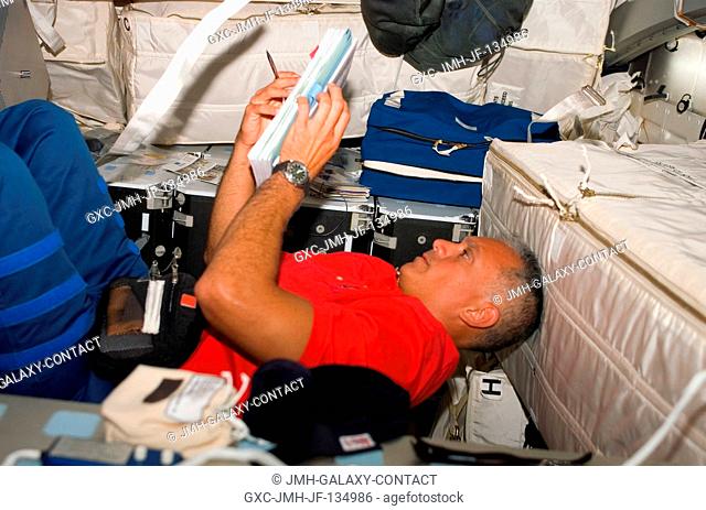 Astronaut John Danny Olivas, STS-117 mission specialist, looks over procedures checklists on the middeck of the Space Shuttle Atlantis