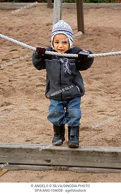 Small boy two and half years of age standing , holding rope in both hands from behind the shoulders , Sweden , Model Release 468
