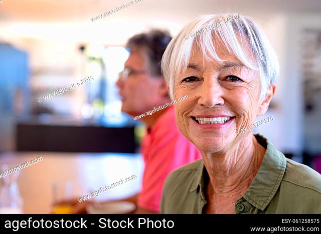 Close-up portrait of smiling asian senior woman sitting with caucasian man in nursing home