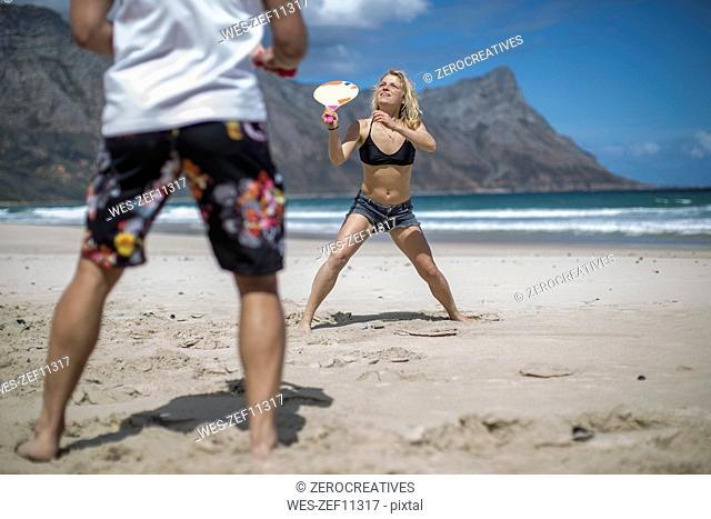 Young couple playing beach paddles on the beach