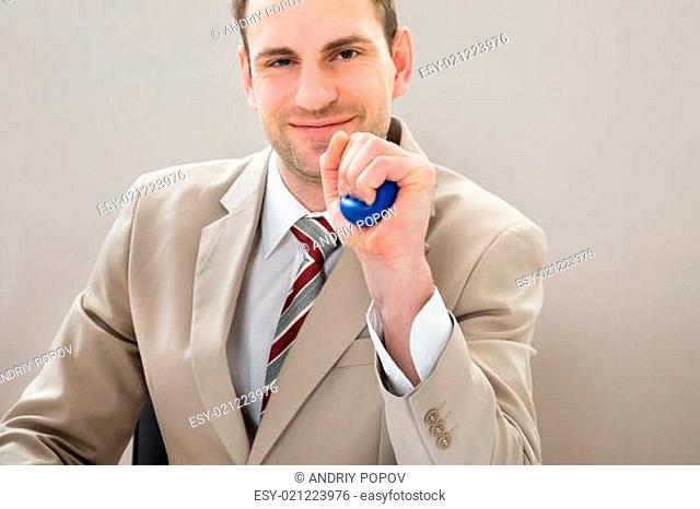 Businessman Squeezing Blue Stress Ball At Desk