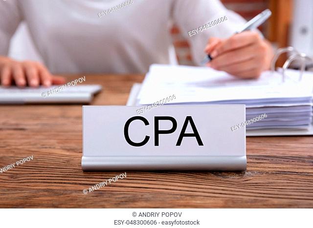CPA Name Plate On The Desk With The Businesswoman Analyzing The Invoice In The Office