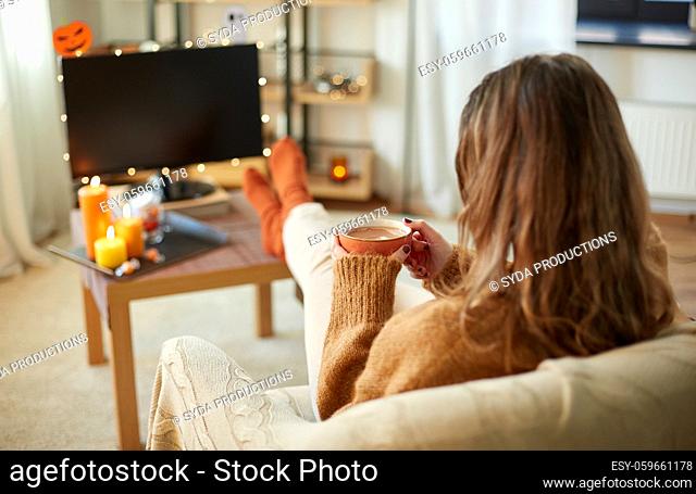 woman watches tv and drinks cocoa on halloween