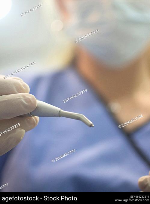 Dental instrumentation dentist pick tooth dental cleaning tool in the hand of dentist wearing face mask in dentists surgery clinic artistic color photo with...
