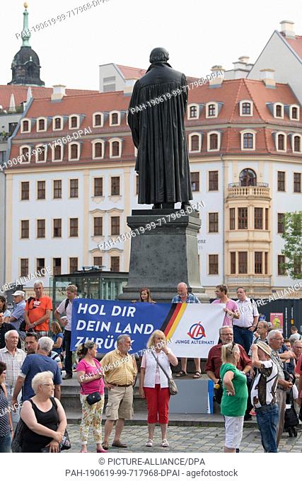 19 June 2019, Saxony, Dresden: On the arrival of Chancellor Merkel, demonstrators from the AFD are standing on Neumarkt with a banner saying ""Get your country...