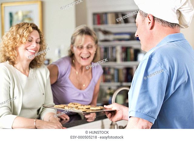 Chef serving cookies to mature women at home