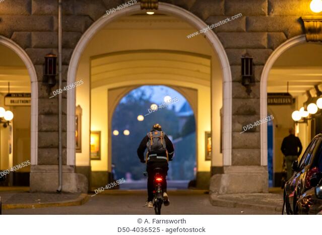 Copenhagen, Denmark Bicyclists at night pass an arched passageway and a sign for the local Det Nu Teater theatre in downtown