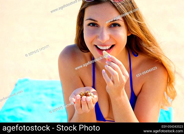 Fitness healthy bikini woman eating mix of nuts seeds dried fruit on the beach