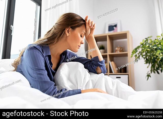 sleepy or stressed woman sitting in bed at home