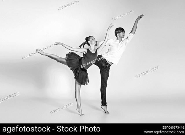 beautiful ballet couple. ballerina in black tutu skirt. man in jeans and white shirt. studio shot. copy space
