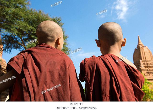 Rear view of two little monks standing under hot sun at Bagan, Myanmar