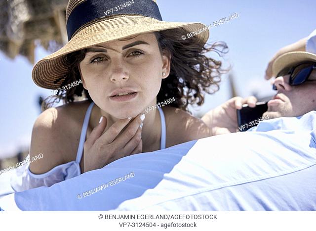 woman enjoying summer breeze, next to busy business man using phone for call, holiday, summer, vacations, couple, work-life balance