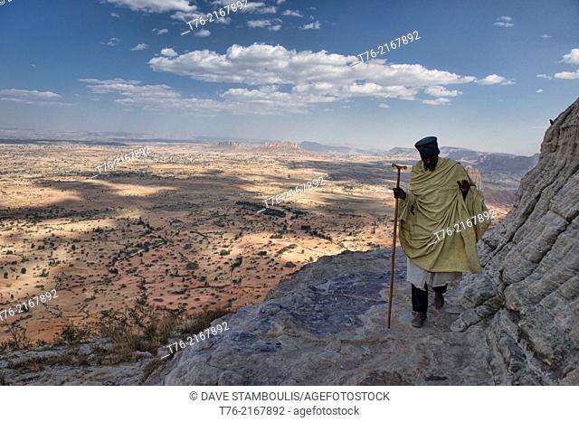 Priest looking off a rock ledge from the Daniel Korkor church in Tigray, Ethiopia