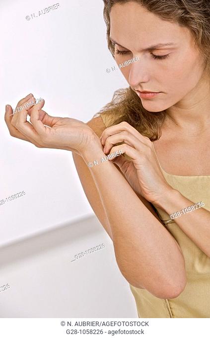 young woman scratching the inside of her wrist because of an itching sensation