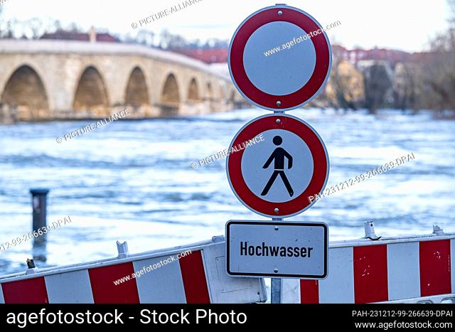 12 December 2023, Bavaria, Regensburg: A sign near the Stone Bridge warns of flooding on the Danube. According to experts
