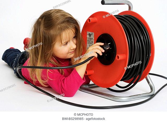 little girl lying on the belly playing with a cable drum