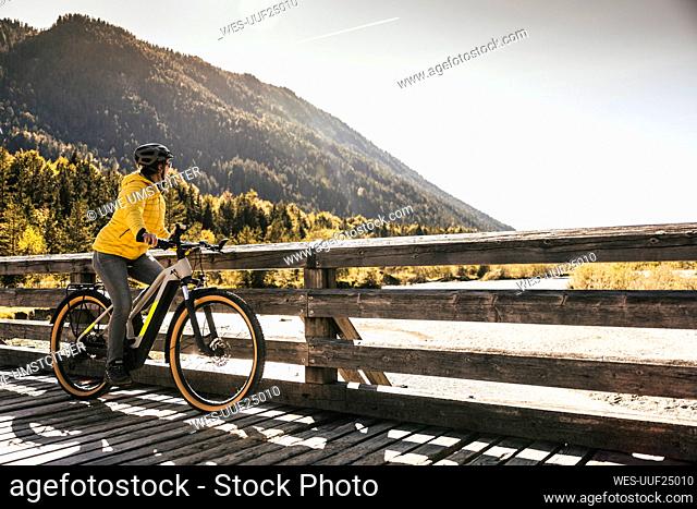 Woman with bicycle looking at mountain on sunny day