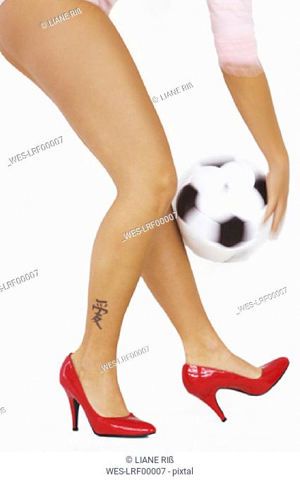 Woman with red high heels holding soccer ball