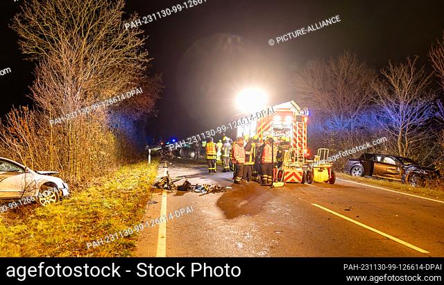 29 November 2023, Hesse, Riedstadt: Firefighters work in the middle of three vehicles involved in an accident. Two people were seriously injured in a head-on...