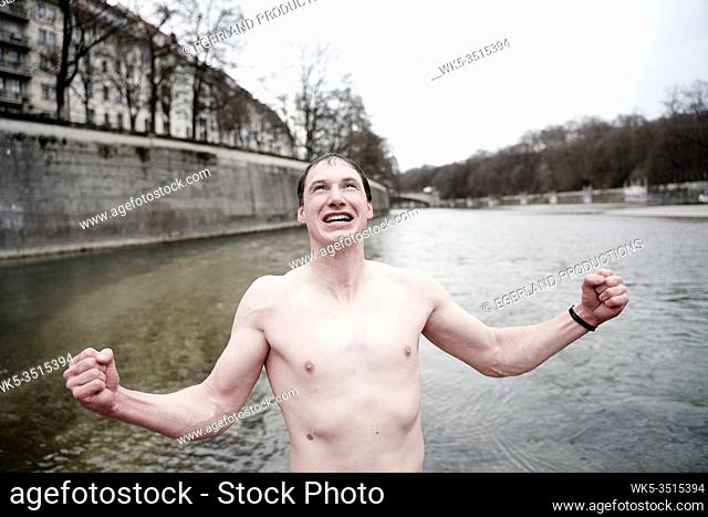 ice bathing, man rejoicing after swimming in cold river Isar, Munich, Germany, in January during winter