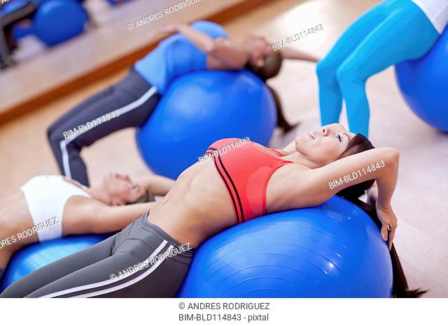 Hispanic women using exercise balls in gym