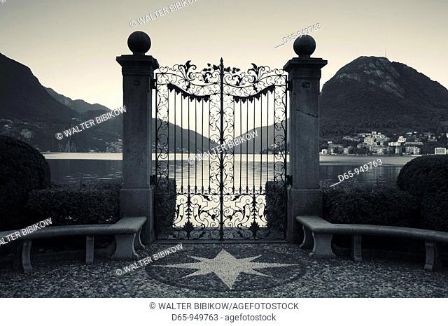 Switzerland, Ticino, Lake Lugano, Lugano, Parco Civico gate view of Monte San Salvador, dawn