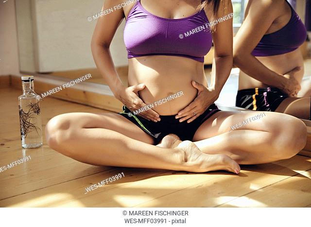 Sporty pregnant woman sitting on floor in exercise room