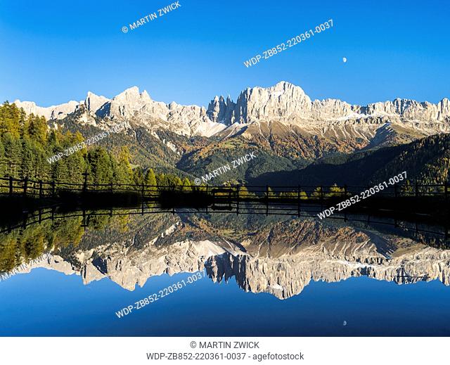 Rosengarten also called Catinaccio mountain range in the Dolomites of South Tyrol (Alto Adige) during autumn. Reflexion of the main peaks in a pond during late...