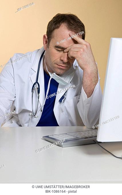Over-worked doctor sitting behind his computer